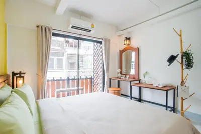 a bedroom with a white bed and a window at Banthat Thong Hostel in Bangkok