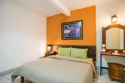 a bedroom with a bed with an orange wall at Banthat Thong Hostel in Bangkok