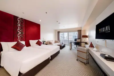 a hotel room with two beds and a desk at Furama Silom Hotel in Bangkok