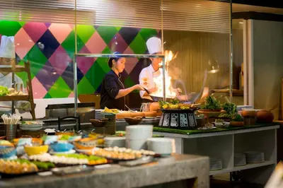 two chefs preparing food in a restaurant kitchen at Furama Silom Hotel in Bangkok