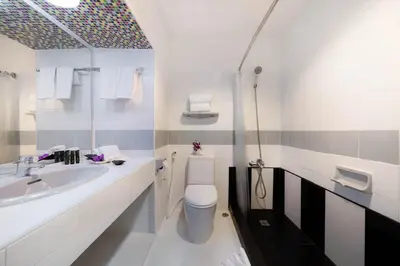 a white bathroom with a toilet and a sink at Furama Silom Hotel in Bangkok
