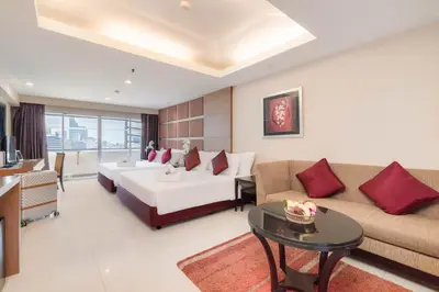 a hotel room with a bed and a couch and a table at Furama Silom Hotel in Bangkok