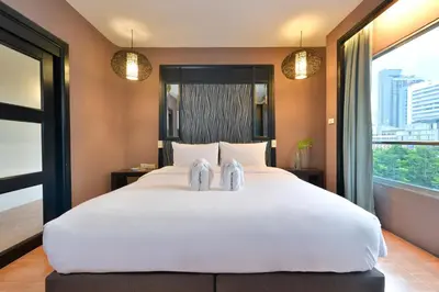 a bedroom with a large white bed with two shoes on it at Royal View Resort - Rang Nam in Bangkok