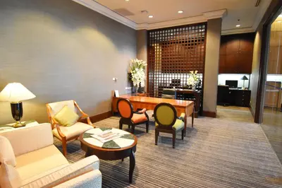 a living room with a couch and a table and chairs at Century Park Hotel in Bangkok