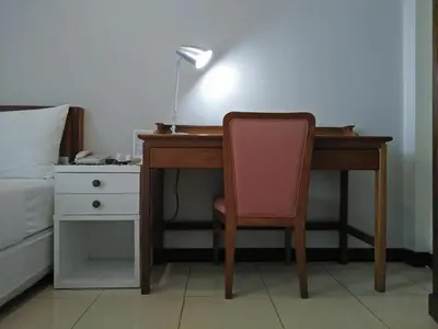 a desk with a chair and a lamp next to a bed at JL Bangkok Hotel in Bangkok