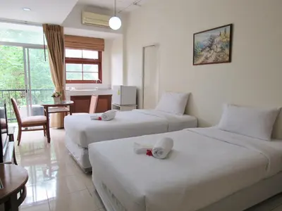 a hotel room with two beds and a desk at JL Bangkok Hotel in Bangkok
