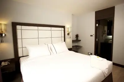 a bedroom with a large white bed with white pillows at Sukhumvit Suites Hotel in Bangkok