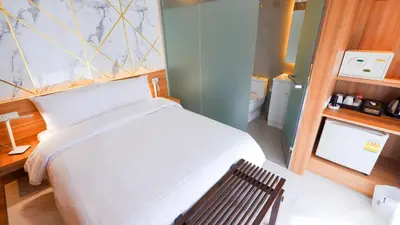 a bedroom with a white bed and a bathroom at Pinnacle Dream in Bangkok