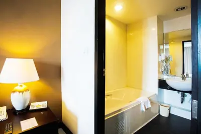 a bathroom with a tub and a sink and a lamp at The Patra Hotel - Rama 9 in Bangkok