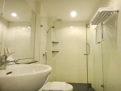 a white bathroom with a shower and a sink at The Patra Hotel - Rama 9 in Bangkok