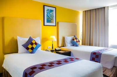 two beds in a hotel room with yellow walls at The Patra Hotel - Rama 9 in Bangkok