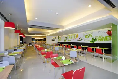 a dining room with tables and red chairs at Ibis Bangkok Sukhumvit 4 in Bangkok