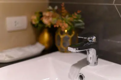 a bathroom sink with a faucet and a vase with flowers at The Mulberry Bangkok Khaosan Road in Bangkok