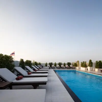 a row of lounge chairs next to a swimming pool at The Mulberry Bangkok Khaosan Road in Bangkok