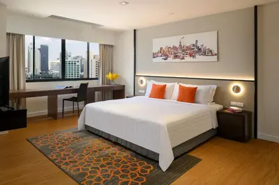 a bedroom with a bed and a desk with a computer at PARKROYAL Suites Bangkok in Bangkok