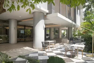 a courtyard with tables and chairs in a building at PARKROYAL Suites Bangkok in Bangkok