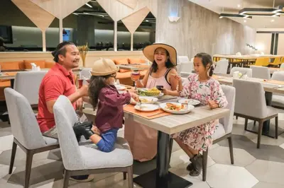 a family eating food at a table in a restaurant at PARKROYAL Suites Bangkok in Bangkok