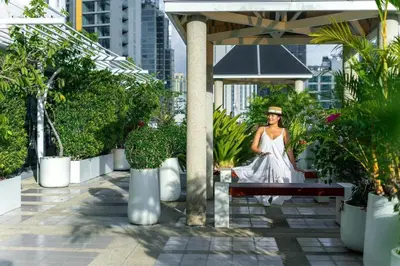 a woman in a white dress sitting on a bench at PARKROYAL Suites Bangkok in Bangkok