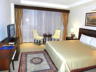 a hotel room with a bed and a desk and a television at De Arni Bangkok - SHA Extra Plus in Bangkok