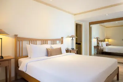 a bedroom with a large white bed and a mirror at Riverfront Bangkok in Bangkok