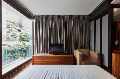 a bedroom with a bed and a chair and a window at LUXX Langsuan Hotel - SHA Plus in Bangkok