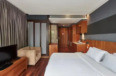 a bedroom with a bed and a couch and a television at LUXX Langsuan Hotel - SHA Plus in Bangkok