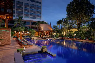 a hotel swimming pool with benches and a building at Ramada Plaza by Wyndham Bangkok Menam Riverside in Bangkok