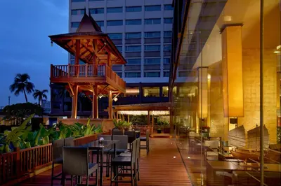 a restaurant with tables and chairs outside of a building at Ramada Plaza by Wyndham Bangkok Menam Riverside in Bangkok