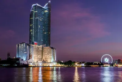 a tall building with a ferris wheel at night at Ramada Plaza by Wyndham Bangkok Menam Riverside in Bangkok