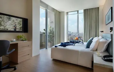 a bedroom with a bed and a desk and a window at Somerset Sukhumvit Thonglor Bangkok in Bangkok