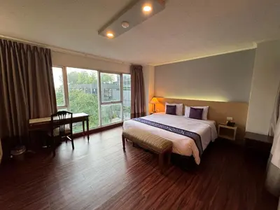 a hotel room with a bed and a desk and window at Collection O The Step Sathorn in Bangkok