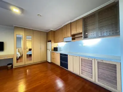 a large kitchen with wooden cabinets and a hard wood floor at Collection O The Step Sathorn in Bangkok