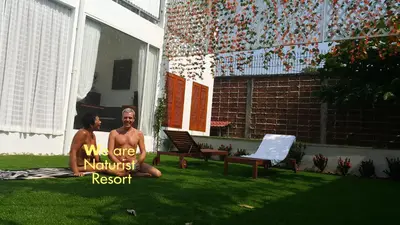a man and a woman sitting on the grass at Barefeet Naturist Resort in Bangkok