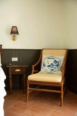a chair in a room with a table and a lamp at Villa Mungkala in Bangkok