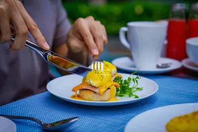 a person eating a plate of food with a fork and knife at Marriott Executive Apartments Bangkok, Sukhumvit 101 in Bangkok