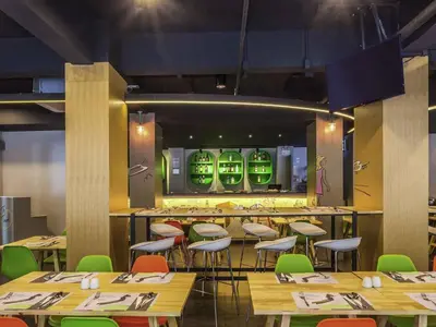 a restaurant with tables and chairs and a bar at Ibis Styles Bangkok Sukhumvit 50 in Bangkok