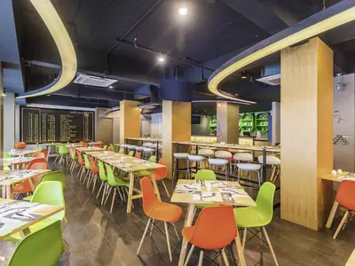 a dining room with tables and chairs in a restaurant at Ibis Styles Bangkok Sukhumvit 50 in Bangkok