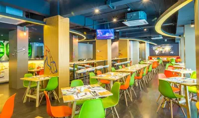 a restaurant with tables and chairs in a room at Ibis Styles Bangkok Sukhumvit 50 in Bangkok