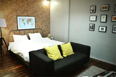 a bedroom with a bed and a black couch at GOODFELLAS THONG LO HOSTEL #No check in after 5pm - Check in time needed# in Bangkok
