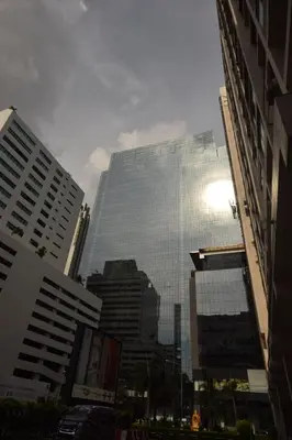a tall glass building in a city with buildings at Blissotel Ratchada in Bangkok