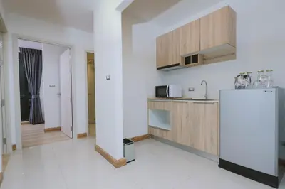 a kitchen with a refrigerator and wooden cabinets at Kokotel Bangkok Sukhumvit 50 in Bangkok