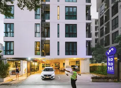 a man standing in a parking lot in front of a building at Kokotel Bangkok Sukhumvit 50 in Bangkok