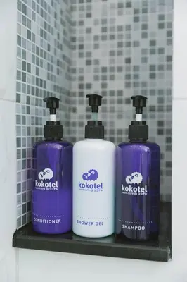 three bottles of soap on a shelf in a bathroom at Kokotel Bangkok Sukhumvit 50 in Bangkok