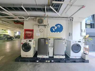 a laundry room with three washing machines and a wall at Kokotel Bangkok Sukhumvit 50 in Bangkok