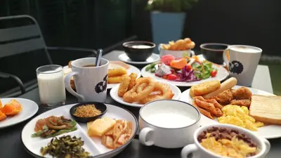 a table with plates of food and cups of milk at Kokotel Bangkok Sukhumvit 50 in Bangkok