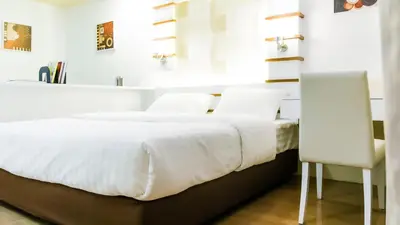 a white bedroom with a bed and a chair at Sunset Residence Pinklao in Bangkok