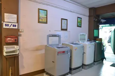 three old fashioned washers and dryers are lined up against a wall at The Backpacker stn in Nonthaburi