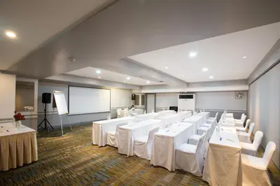 a conference room with white tables and chairs and a screen at imm hotel Ladprao Bangkapi Bangkok in Bangkok