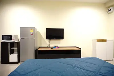a room with a bed and a desk and a television at The Arni Sukhumvit 101 in Bangkok