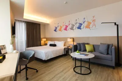 a hotel room with a bed and a couch at Modena by Fraser Bangkok in Bangkok
